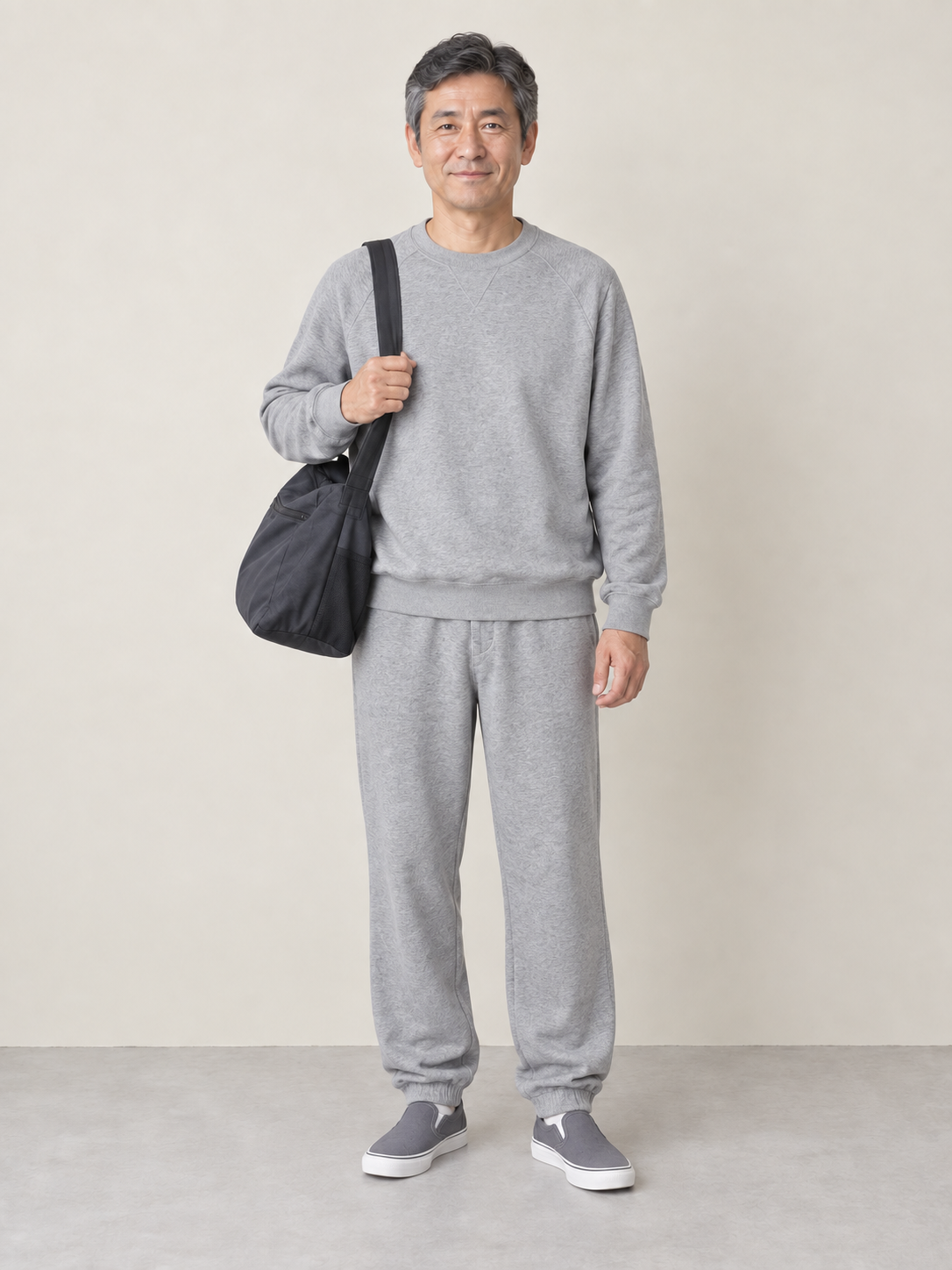 グレーのスウェット上下と柔らかいバッグを合わせた50代男性の服装例